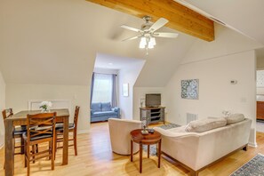 Ett loftliknande vardagsrum med matplats, soffa, TV och en takfläkt.