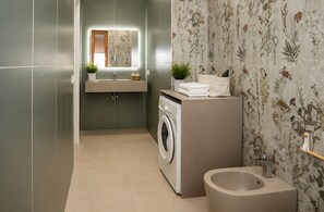Un baño pequeño con lavadora, lavamanos con espejo e inodoro.