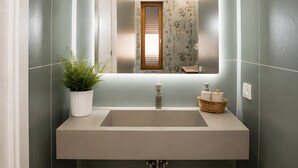 A bathroom with a large mirror, a sink, a potted plant, and a window with blinds. - Holiday Home 'Vacanza Via Roma 103 F' with Sea View and Wi-Fi (Crotone)