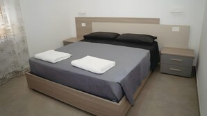 A neatly made bed with a headboard, two bedside tables, and a curtain partially drawn. - Holiday Home 'Vacanza Via Roma 103 F' with Sea View and Wi-Fi (Crotone)