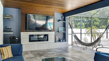 A living room with a TV, sofa, and hammock.
