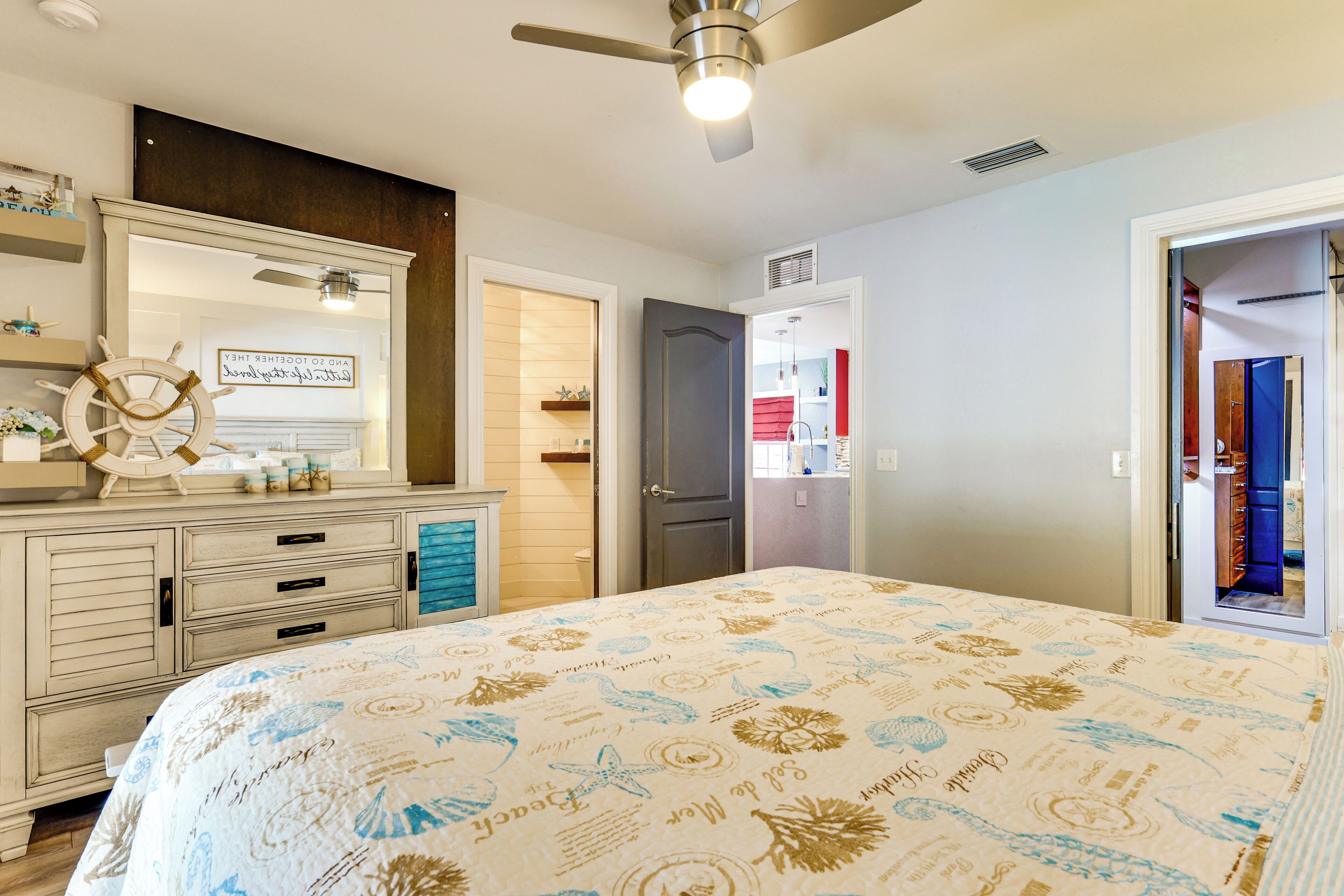 Un dormitorio con cama, cómoda y un espejo grande.