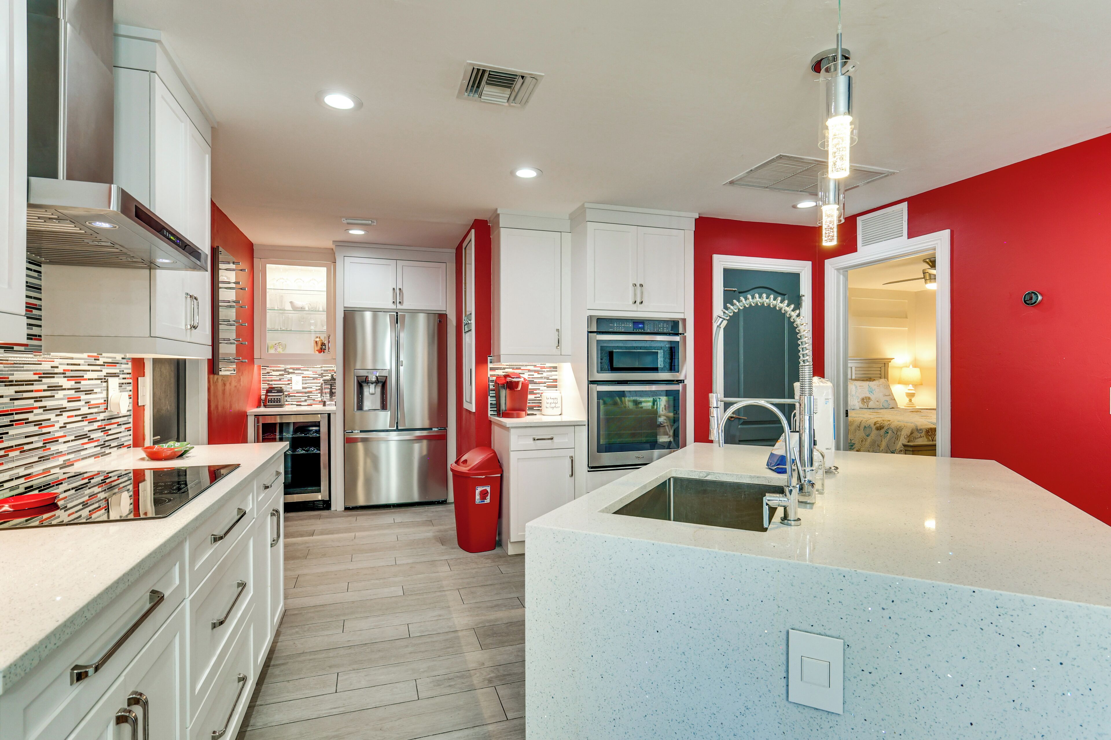 A modern kitchen with stainless steel appliances, a central island, and a red accent wall.