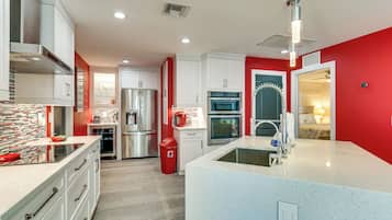 A modern kitchen with stainless steel appliances, a central island, and a red accent wall.