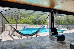 Ein überdachter Außenbereich mit Pool, einer Hängematte und Liegestühlen.