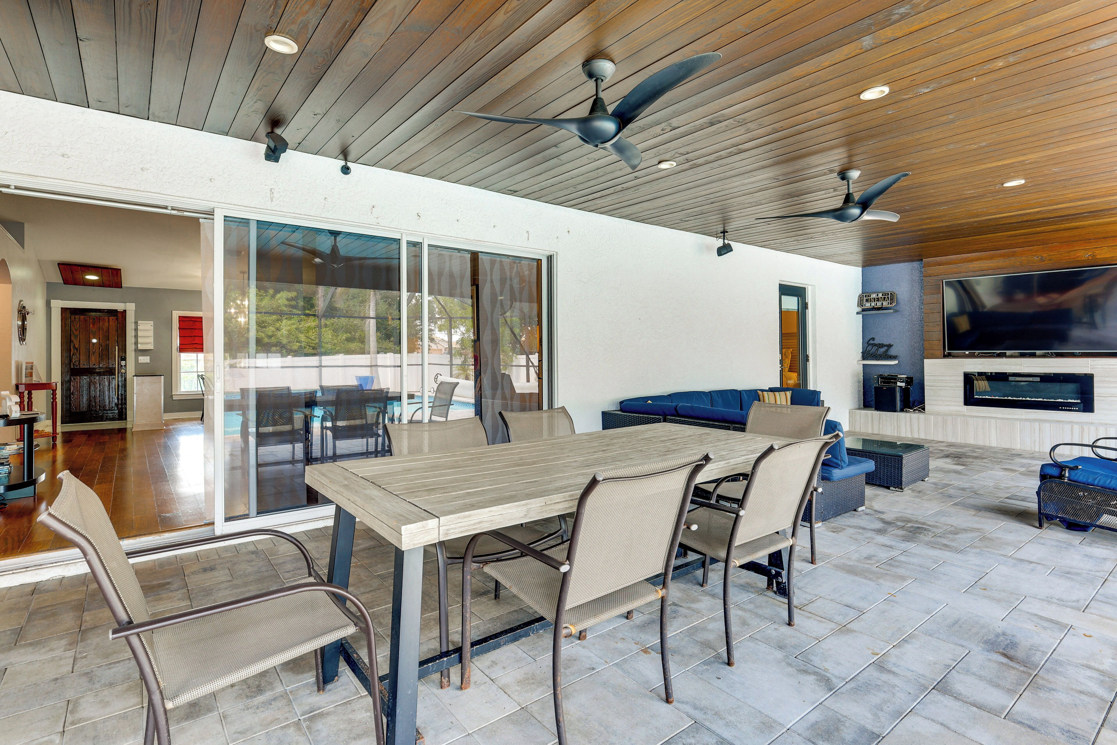 A spacious living area with a large table and chairs, ceiling fans, a TV, and a fireplace.