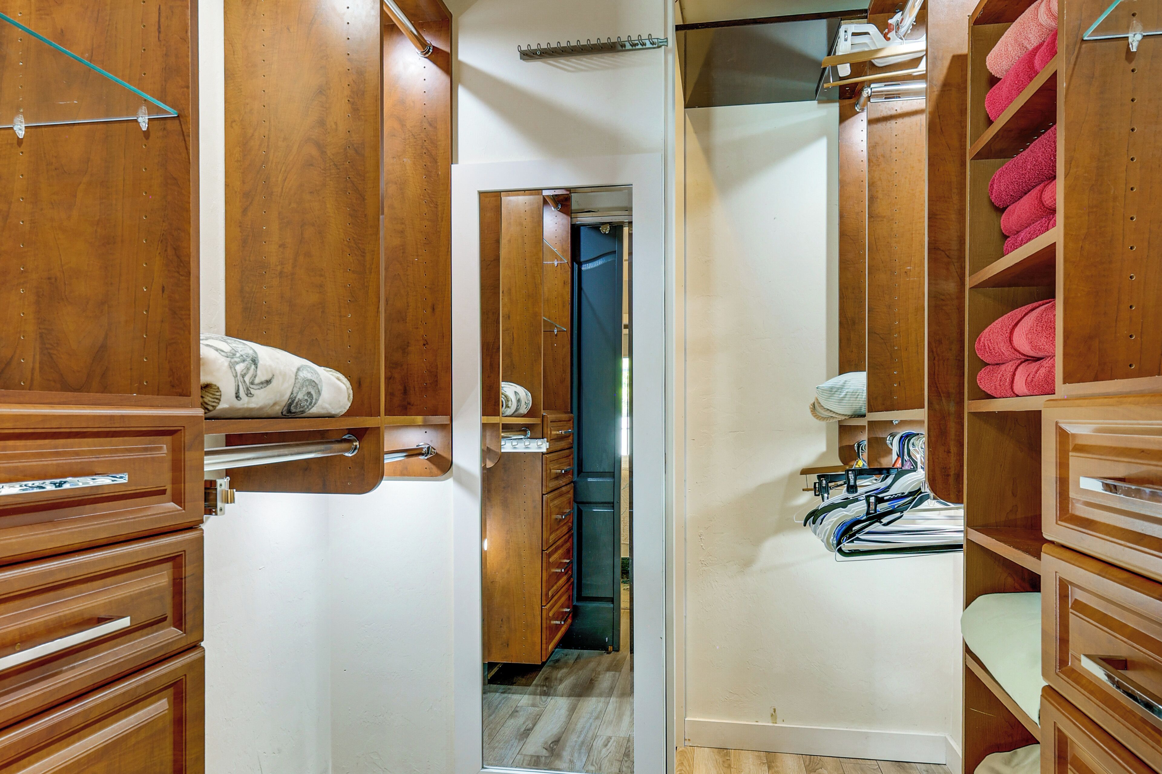 A wooden closet with shelves and drawers, a blue door, and a hallway leading to another room.