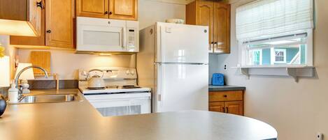 A kitchen with wooden cabinets, a white refrigerator, a stove, and a window with blinds.