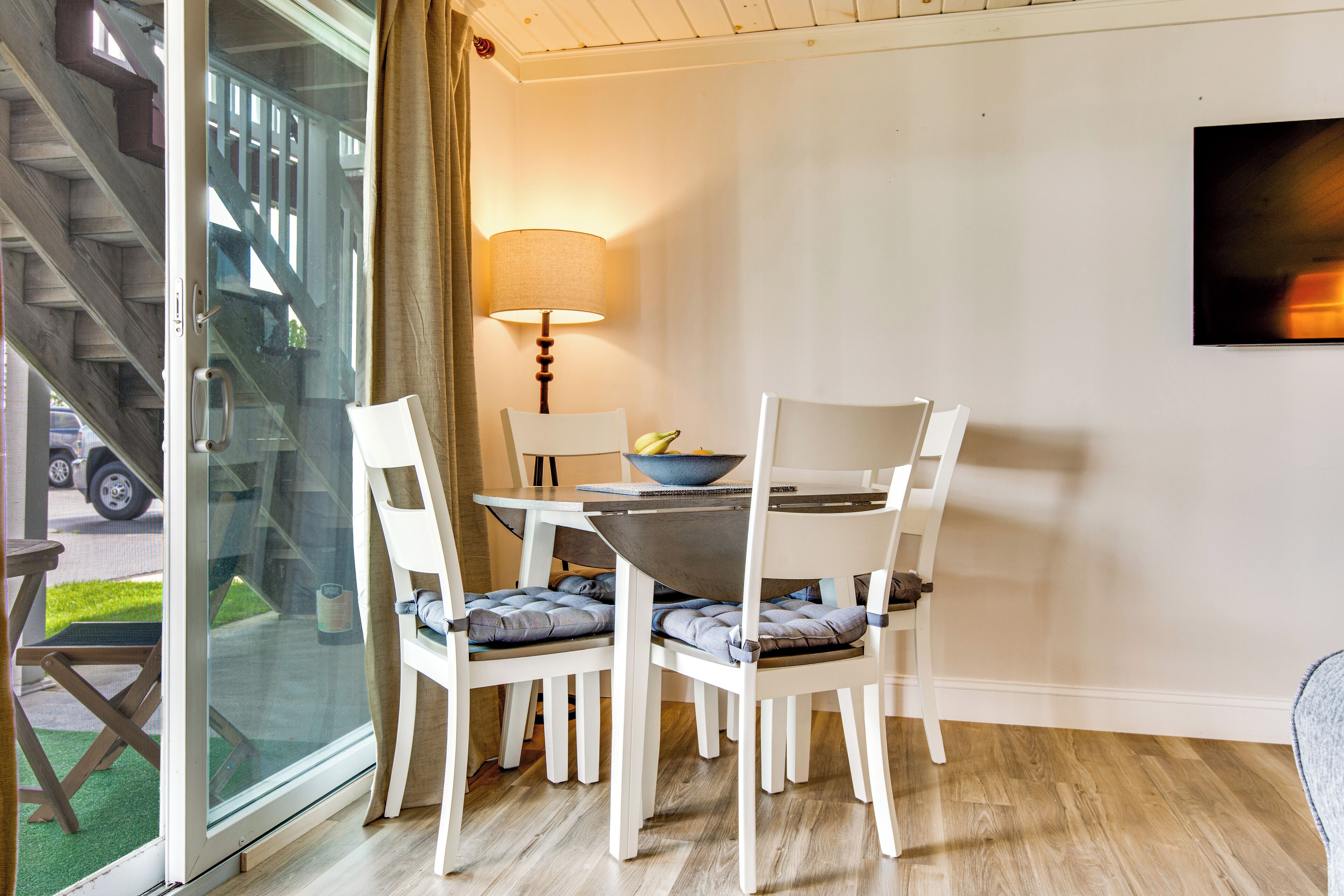 Un comedor con una mesa, sillas, una lámpara y vistas de una escalera.
