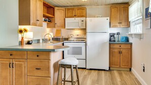 Une cuisine avec des meubles de rangement en bois, un réfrigérateur blanc, un four à micro-ondes et une cuisinière.
