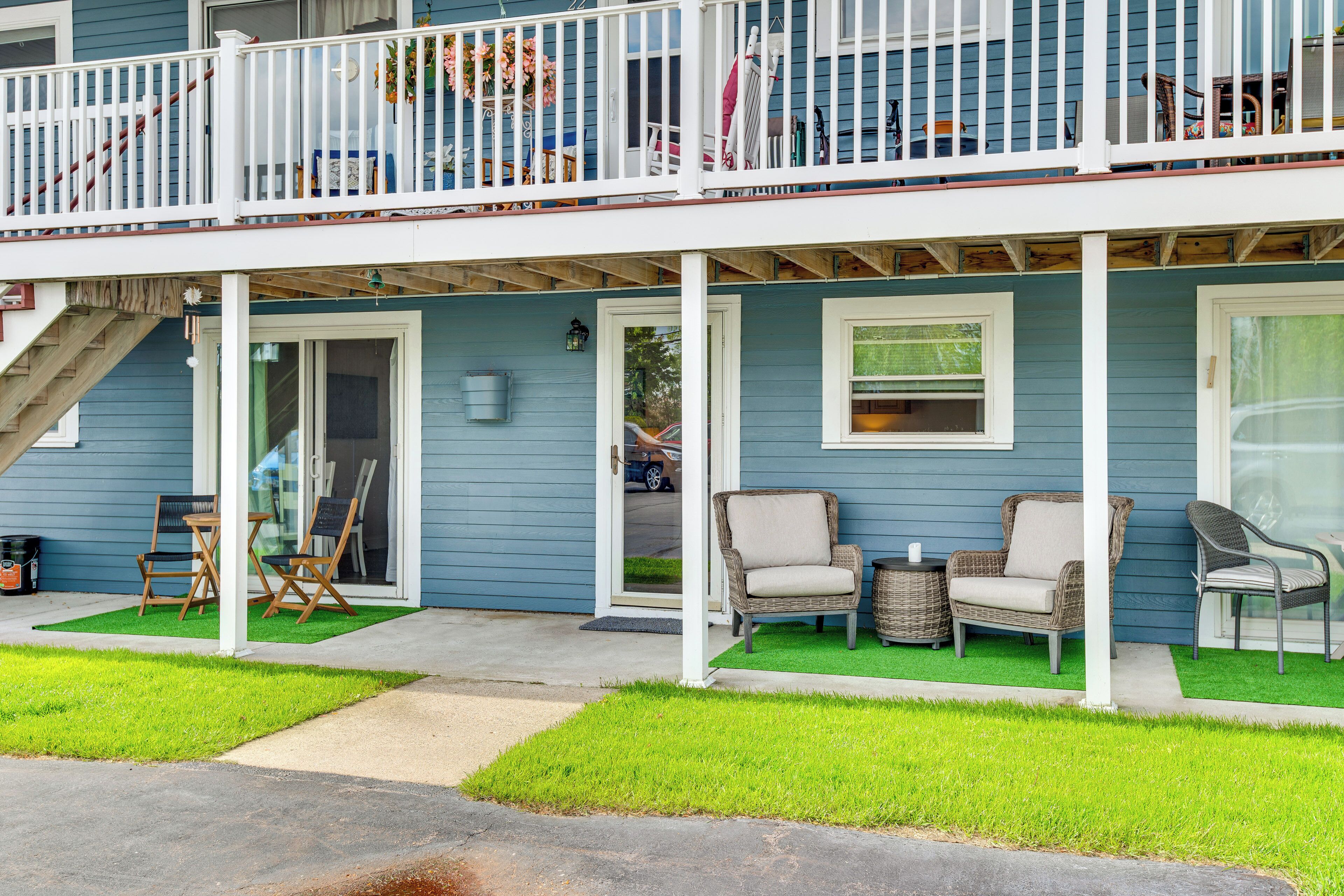 A two-story house with a balcony, outdoor seating, and a front door.