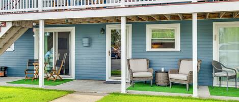 A two-story house with a balcony, outdoor seating, and a front door.
