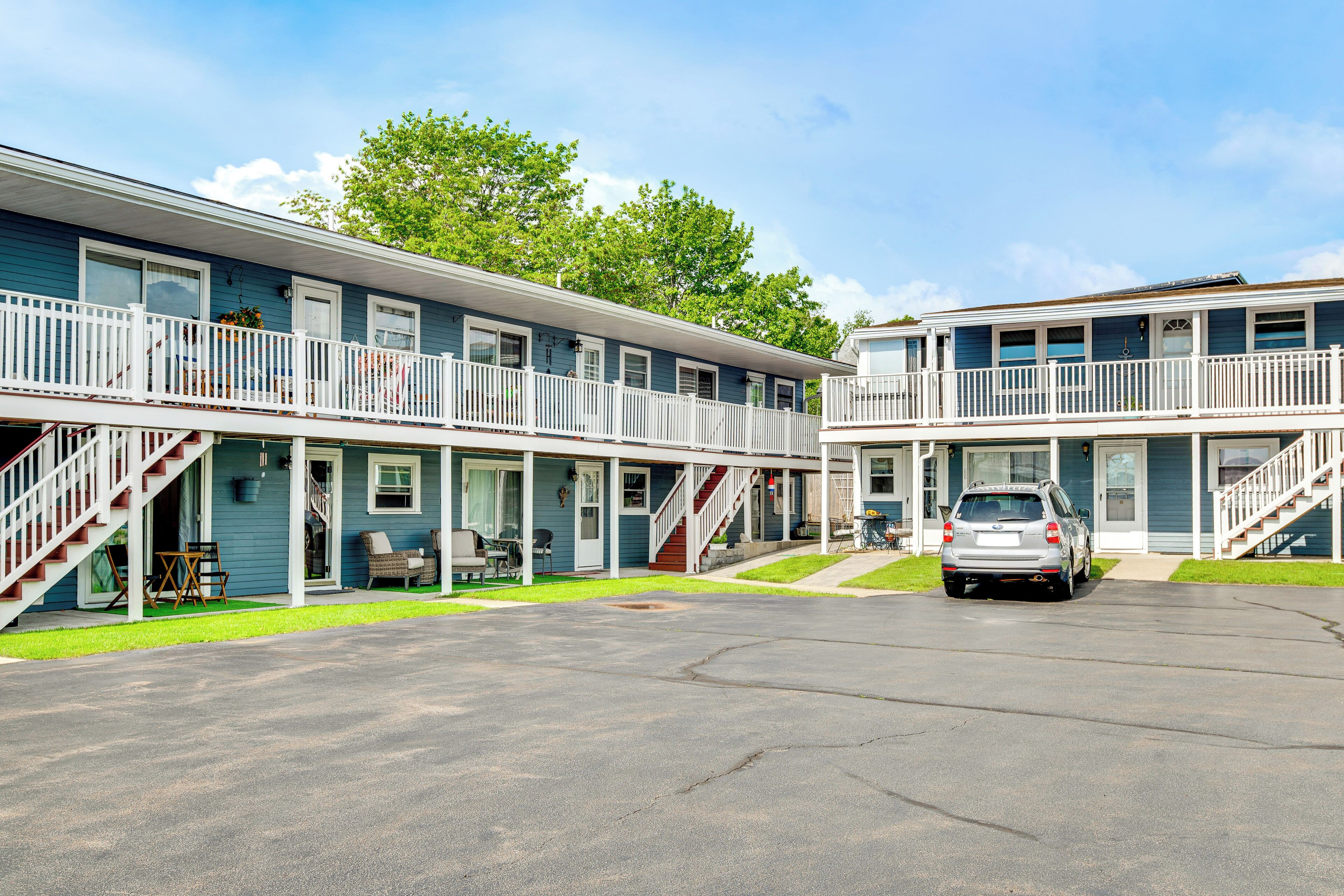 A motel with two-story buildings, a covered parking area, and a car parked in front.
