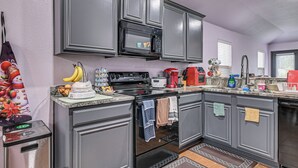 A kitchen with grey cabinets, a microwave, a stove, and a coffee maker. - Great for Traveling Nurses! Charming Mckinney Home (McKinney)