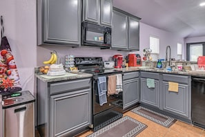 A kitchen with grey cabinets, a microwave, a stove, and a coffee maker. - Great for Traveling Nurses! Charming Mckinney Home (McKinney)