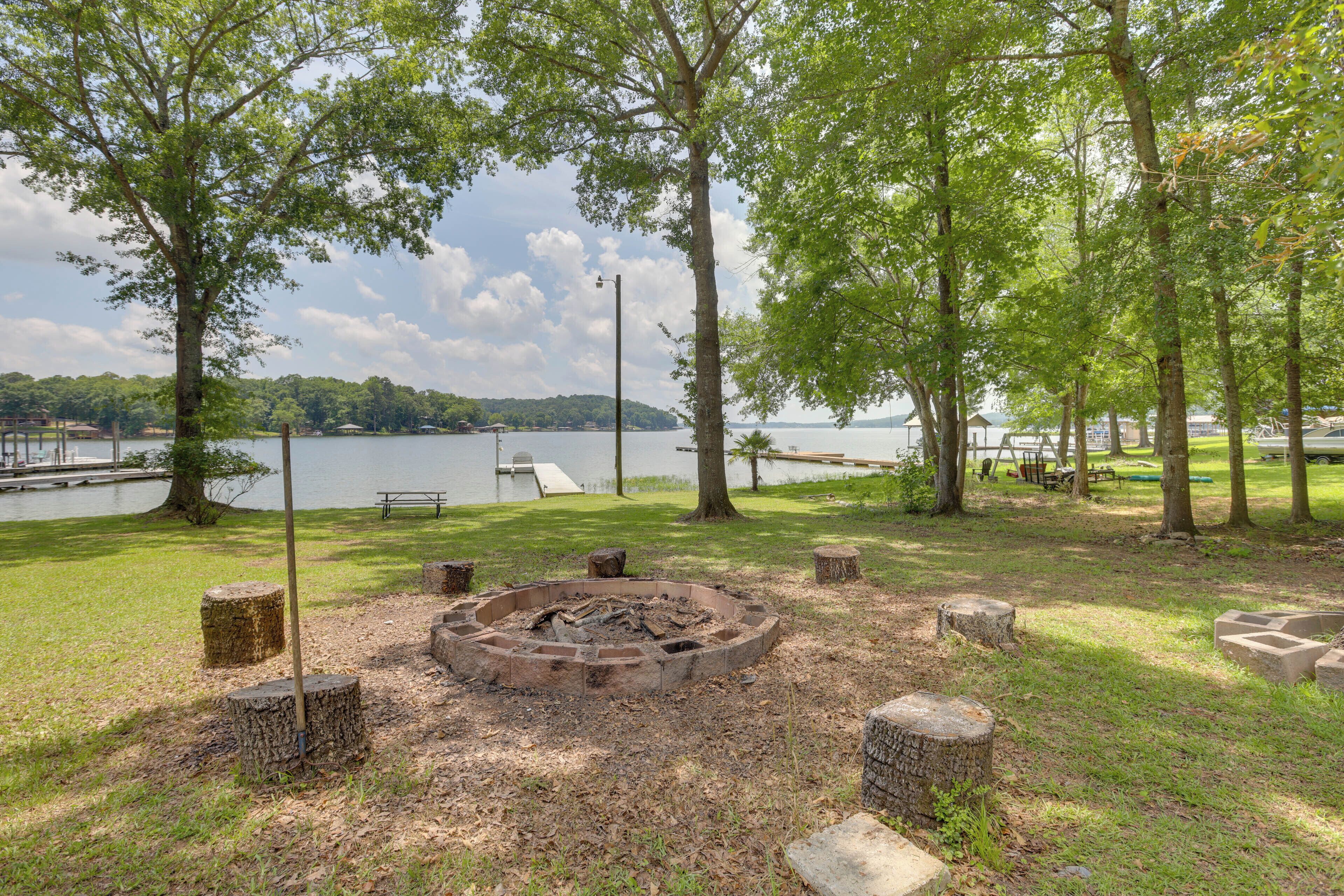 A lakeside park with a fire pit, picnic tables, and a dock.