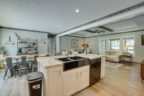 A kitchen with a central island, a dining area with chairs, a sofa, and a coffee table. - Lake Ridge Cove, Logan Martin Lake Family Retreat! (Talladega)
