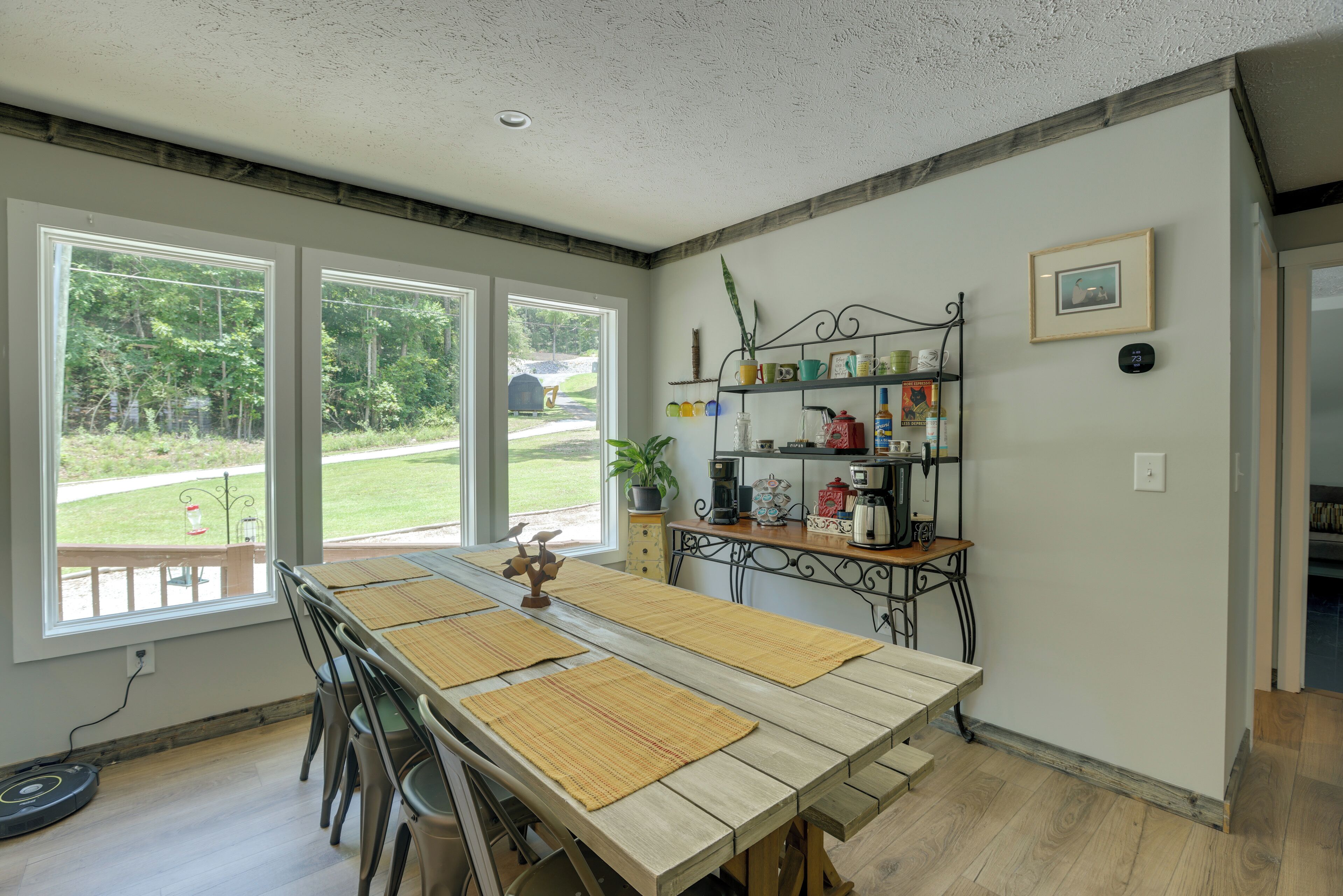 Un espace repas avec une longue table, des chaises et une vue sur l’extérieur.
