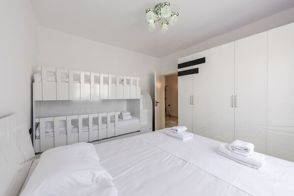 Ein modernes Hotelzimmer mit einem großen Bett, einem weißen Wandschrank und einem durchgegangenen Badezimmer.