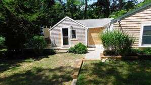 Une maison de plain-pied avec un porche à l’avant, un petit jardin et une terrasse en bois.