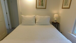 Un lit bien fait, avec du linge de lit blanc, dans une chambre d’hôtel.
