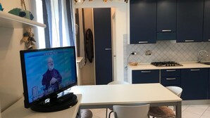 Eine moderne Küche mit dunkelblauen Schränken, einer weißen Arbeitsplatte und einer Essecke mit zwei Stühlen.