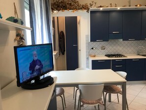 A modern kitchen with dark blue cabinets, a white countertop, and a dining area with two chairs. - La Terrasse - Matteotti 110 (Ospedaletti)