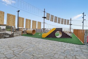 Ein Spielplatz mit Kletterwänden, einer Rutsche und einem Baumstammtunnel.