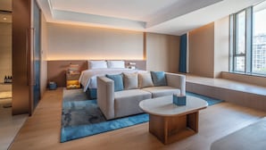 Una habitación de hotel moderna con cama, sofá y una pequeña mesa.