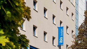 Un edificio con varias ventanas y un banderín azul que dice 'ibis budget'.