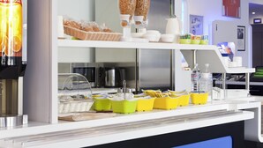 A breakfast bar with a coffee machine, cereal dispensers, and various breakfast items. - Ibis Budget Berlin Ost (Berlin)