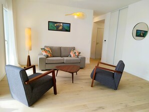 Un soggiorno moderno con un divano grigio, due poltrone, un tavolino in legno e una lampada da terra.