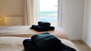 Habitación de hotel con dos camas, una ventana con cortinas, un radiador y un espejo montado en la pared.