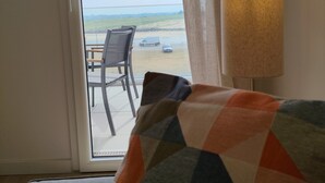 Una habitación con vista al mar, una mesa con sillas y una lámpara.