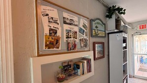Een muur met een ingelijste collage van foto's, een klein boekenrek met boeken, en een bordje met de tekst 'Ons strandhuis'.