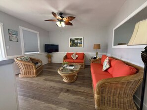 A living room with wicker furniture, a ceiling fan, a flat-screen TV, and a window with blinds. - Oceanfront Hidden Gem in Hollywood Beach (Hollywood)