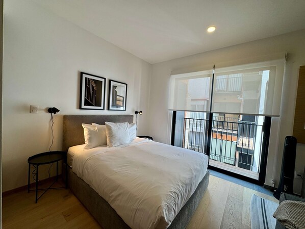 A bedroom with a bed, a nightstand, a wall-mounted lamp, two framed pictures, and a balcony with a railing. - w Upscale Loft w Balcony in Roma Norte (Mexico City)
