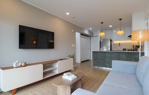 A modern living room with a flat-screen TV, a sofa, a coffee table, and a kitchen area with a bar. - w Upscale 2BR w Balcony View in Miraflores (Lima)