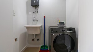Een wasserette met een wasmachine, een wasbak en een bezem.
