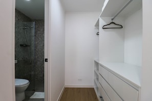 Un baño con ducha, inodoro y un tocador blanco con un perchero.