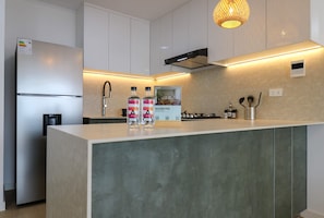 Una cocina moderna con una isla integrada, electrodomésticos de acero inoxidable e iluminación colgante.