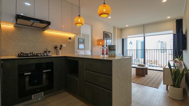 Een moderne keuken met een ingebouwde oven, een gasfornuis en hangende pendelverlichting.