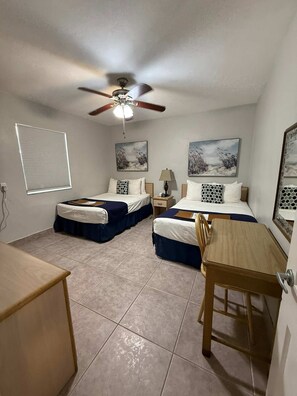 A bedroom with two beds, a ceiling fan, a bedside table with a lamp, and artwork on the walls. - Waterfront Fifa Retreat in Hollywood Beach (Hollywood)