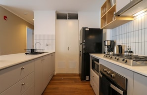 Eine moderne Küche mit einem schwarzen Kühlschrank, einem Herd und einer Kaffeemaschine.