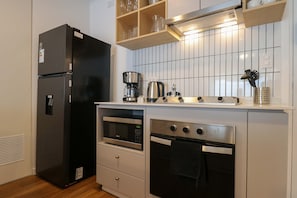 A compact kitchen with a black refrigerator, a microwave, an oven, and a coffee maker. - w Graceful 2BR w Balcony in Miraflores (Lima)