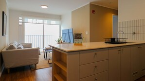 Una cocina moderna con una isla central, un comedor con sofá y vistas al exterior a través de amplios ventanales.