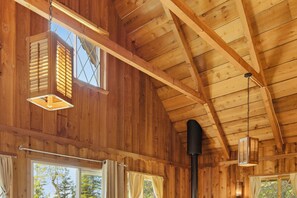 Un interior de madera con techos altos, ventanas grandes y lámparas colgantes.