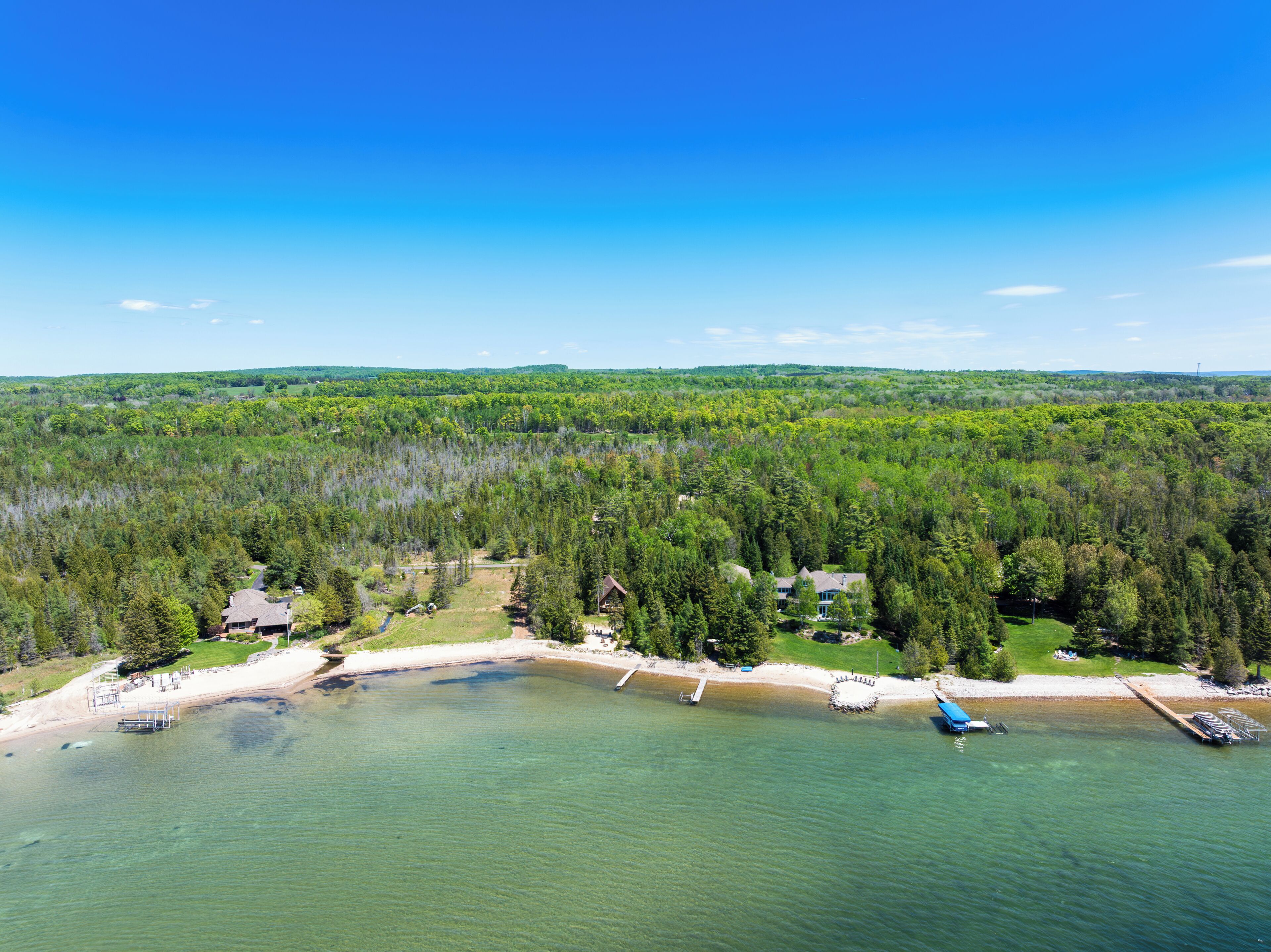 A lakeside property with a dock, a small beach, and a forested area.