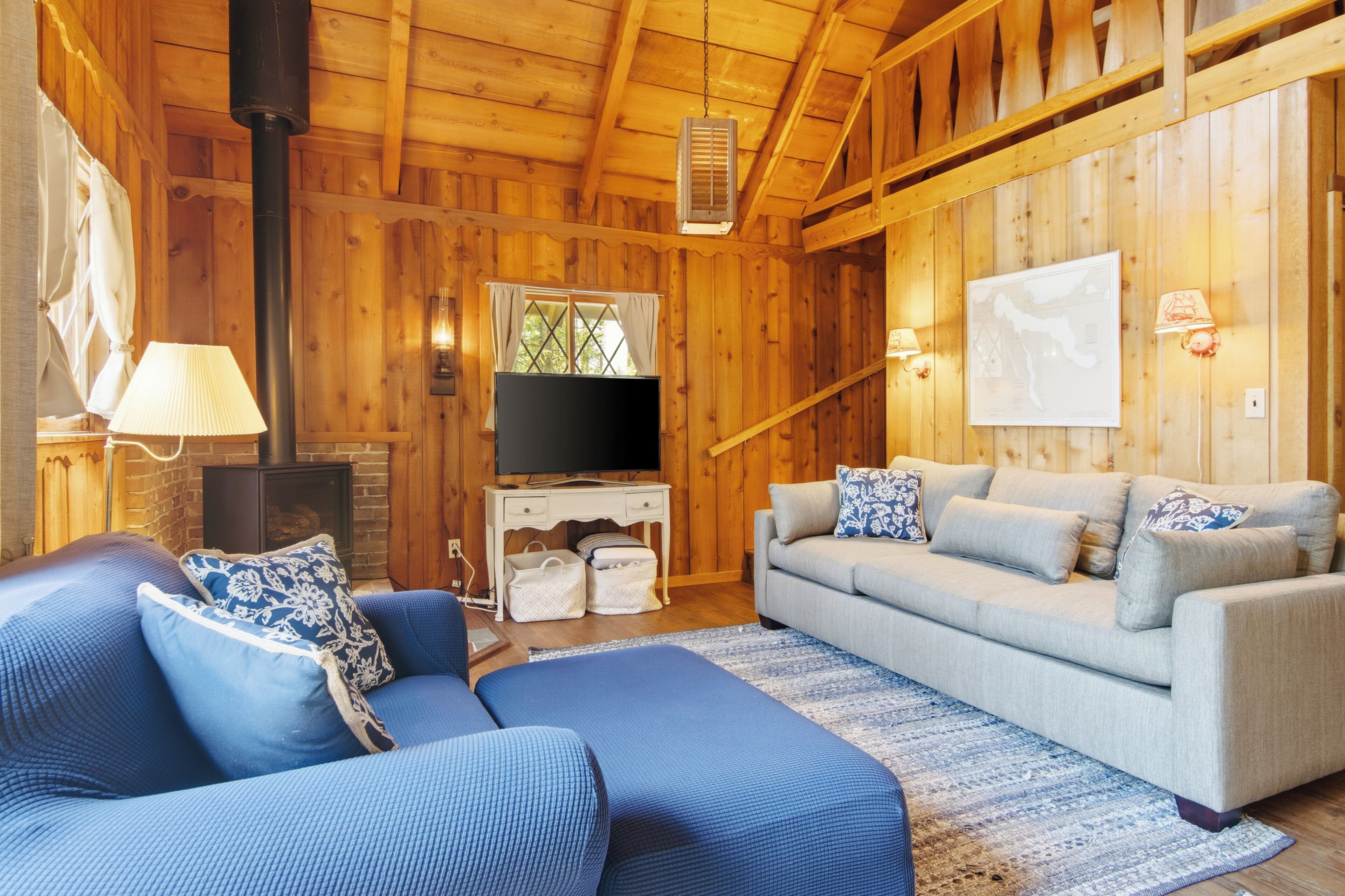 A wooden interior with a sofa, a television, and a fireplace.