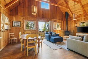A wooden cabin interior with a dining area, sofas, a fireplace, and large windows. - Stunning views of Lake Charlevoix (Charlevoix)